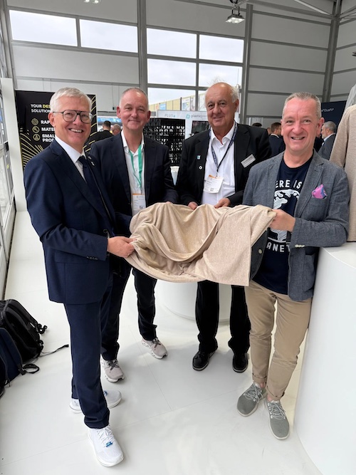 The same representatives holding the new fabric made from 100% recycled polyester at the Edvanced Recycling Center, where EREMA demonstrates live recycling and products made of recyclate during the K show. © 2025 EREMA The same representatives holding the new fabric made from 100% recycled polyester at the Edvanced Recycling Center, where EREMA demonstrates live recycling and products made of recyclate during the K show. © 2025 EREMA